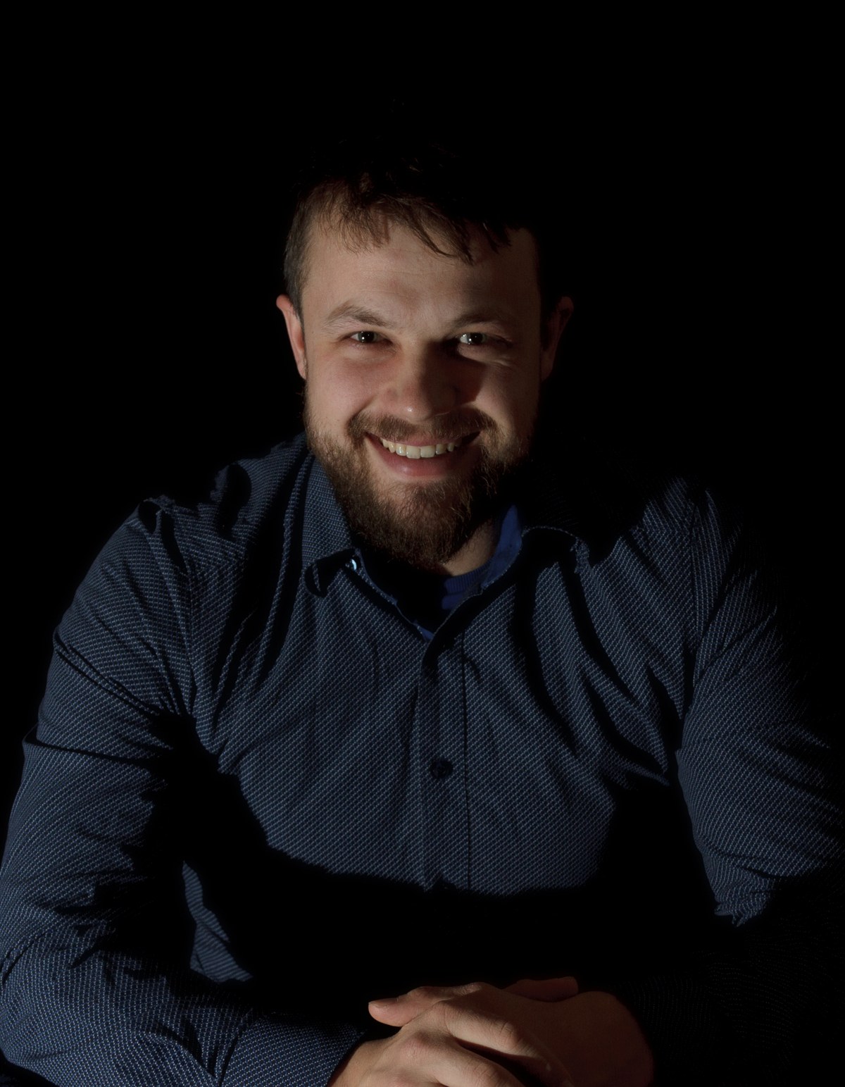 Paul Jung, lächelnd, im dunklen Hemd, die Hände gefaltet